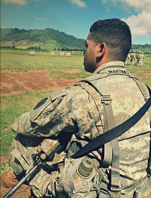 Soldier sitting in the grass looking off in the distance