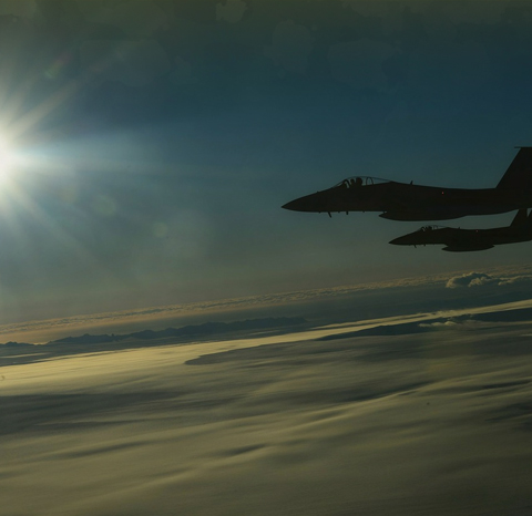 Two fighter jets flying over clouds